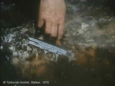 Stalker, Photogramme - Plan 108.  Gros plan du revolver, la main du Stalker pousse et enfonce le revolver dans l’eau.