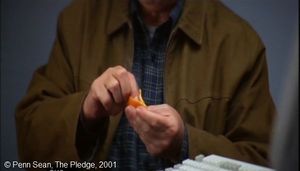  The Pledge  de Sean Penn.  Photogramme – Épluchure 3.  0h 42’ 05’’.  Jerry fume une cigarette et l’écrase dans l’épluchure d’une orange.