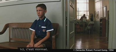 Forrest Gump de Robert Zemeckis. Photogramme banc 7 : Dans le couloir du lycée, Forrest est assis sur un banc, la tête droite, les mains posées sur les genoux, attendant sagement sa mère.
