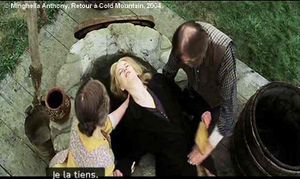 Retour à Cold Mountain de Minghella Anthony. Photogramme Puits 2. Sally et Esco tiennent Ada afin qu'elle puisse regarder dans le fond du puits. Ada tient de la main gauche un miroir rectangulaire.