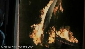 Photogramme - Bateau 3 : Mathilde, Plan 1699. De Petris regarde dehors. Nous avons une illusion d’un bateau en feu. De Petris se retourne vers l’enfant et lui dit : « Il n’y a rien, là-bas. Allez donne-moi l’arme. »