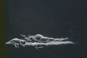 Photogramme - Chambre 4 : Nostalghia, Plan 35a. La femme enceinte du Poète allongée sur le lit, parallèle au mur.