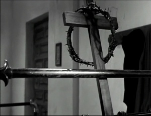  Viridiana de Luis Buñuel.     Photogramme 57 - Plan 76a. Plan rapproché sur la croix de bois noir et la couronne d’épines accrochées au lit.