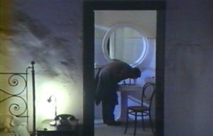 Photogramme - Porte 10 : Nostalghia, Plan 27c. A travers la porte de la salle de bain, le Poète dispose un gobelet sur le bord du lavabo, pour finalement boire directement au robinet. Pourquoi ?