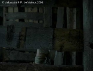 Le Visiteur, photogramme - plan 134b, ensuite, à travers une ouverture de l'étable (barrage), nous observons une scène insolite : l'Enfant va enrouler minutieusement et très calmement, la corde autour de sa petite taille.